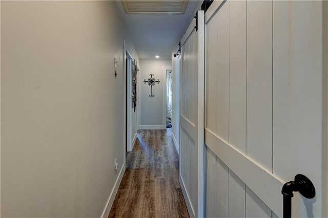 hallway with a barn door and hardwood / wood-style floors