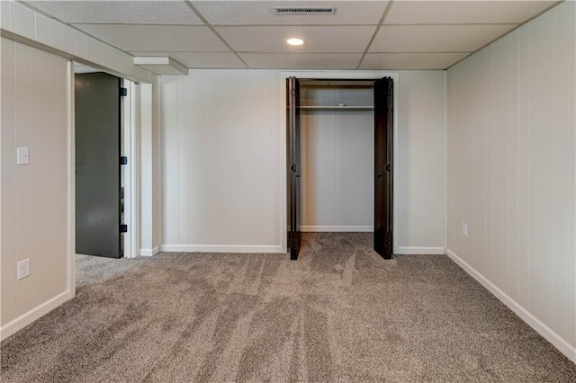 unfurnished bedroom featuring carpet, a drop ceiling, and a closet