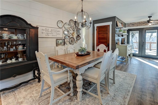 dining space featuring french doors, a notable chandelier, hardwood / wood-style floors, and wood walls