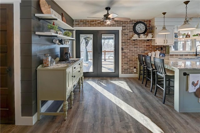 kitchen featuring pendant lighting, a kitchen breakfast bar, brick wall, dark hardwood / wood-style flooring, and french doors