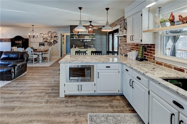 kitchen with stainless steel microwave, hanging light fixtures, and white cabinets