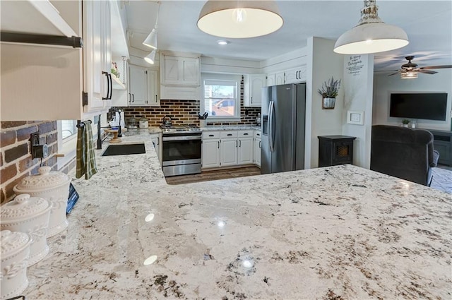 kitchen featuring sink, appliances with stainless steel finishes, white cabinets, decorative backsplash, and decorative light fixtures