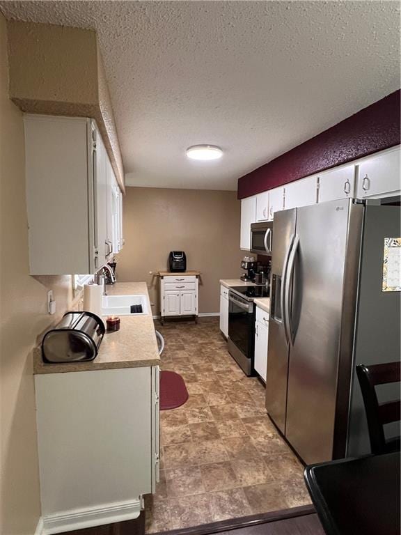 kitchen with white cabinetry, appliances with stainless steel finishes, sink, and a textured ceiling