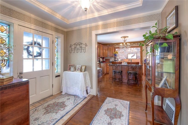 foyer entrance with an inviting chandelier, ornamental molding, and wood-type flooring