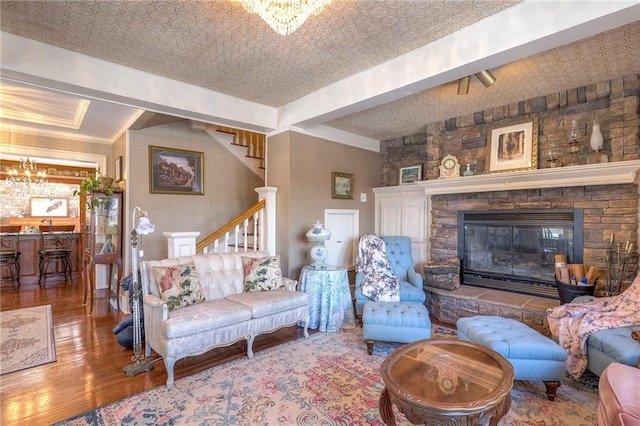 living room featuring an inviting chandelier, hardwood / wood-style floors, a fireplace, and lofted ceiling with beams