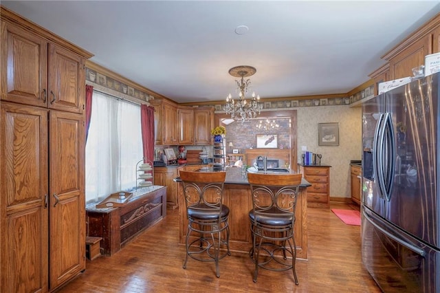 kitchen with dark hardwood / wood-style floors, a kitchen island with sink, stainless steel fridge with ice dispenser, and a breakfast bar area