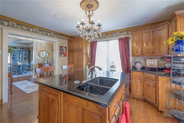 kitchen with sink, a center island with sink, a notable chandelier, pendant lighting, and light hardwood / wood-style floors