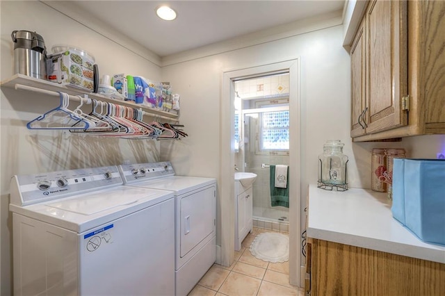 clothes washing area with separate washer and dryer, light tile patterned floors, and cabinets