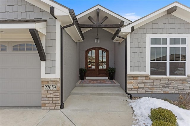 snow covered property entrance featuring french doors and a garage