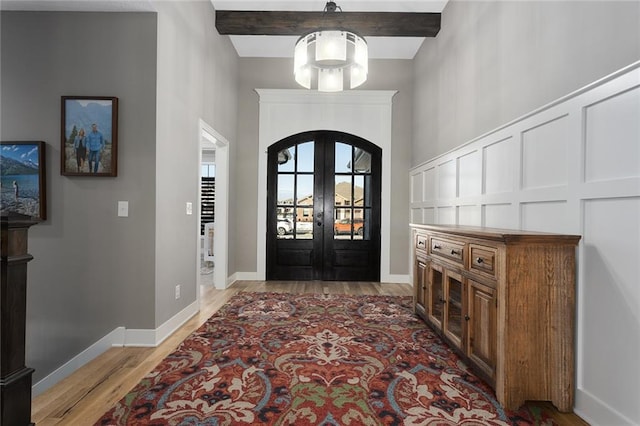 entrance foyer featuring light wood-type flooring, beam ceiling, and french doors