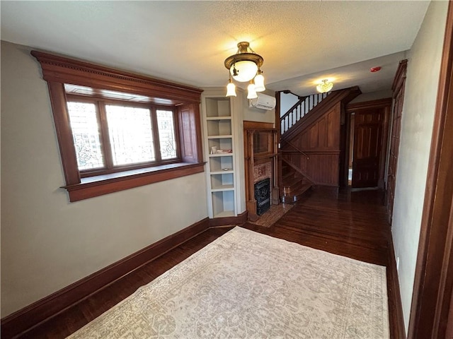 spare room featuring built in shelves, a wall mounted air conditioner, and dark hardwood / wood-style flooring