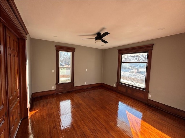 spare room with ceiling fan, a healthy amount of sunlight, and dark hardwood / wood-style flooring