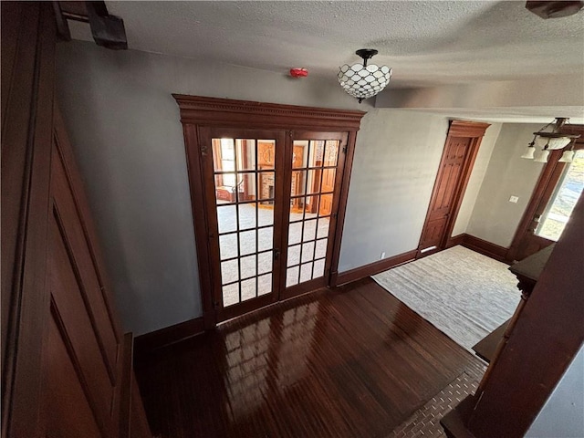 doorway to outside featuring a textured ceiling, dark hardwood / wood-style floors, and french doors