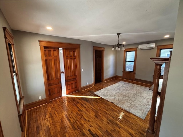 foyer with a notable chandelier, an AC wall unit, and dark wood-type flooring