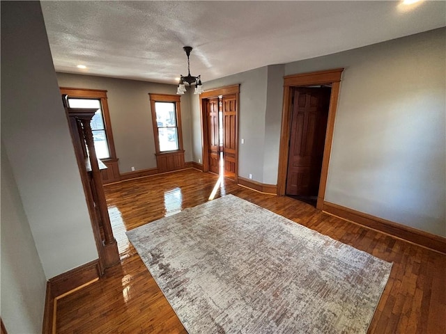 spare room featuring dark wood-type flooring, a textured ceiling, and a chandelier