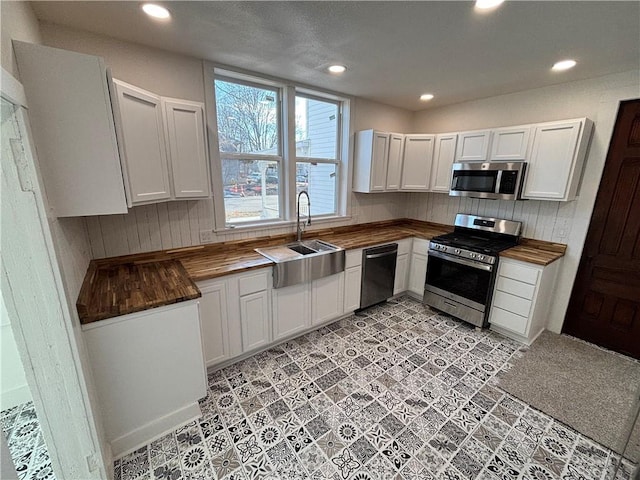 kitchen with white cabinetry, butcher block counters, and appliances with stainless steel finishes