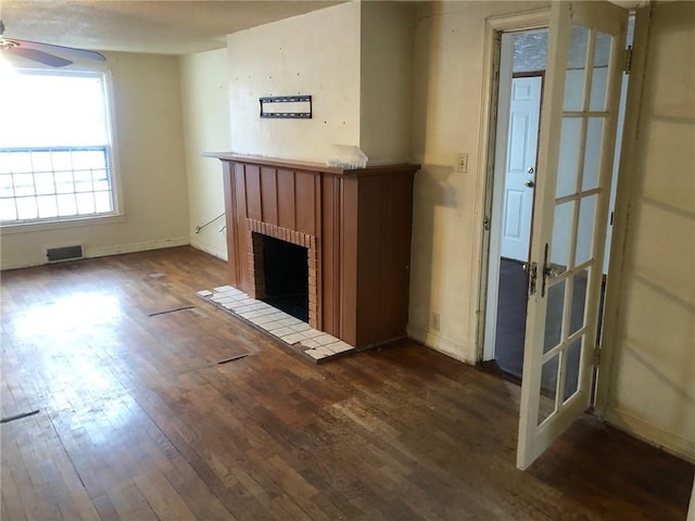 unfurnished living room featuring ceiling fan, a fireplace, and dark hardwood / wood-style flooring