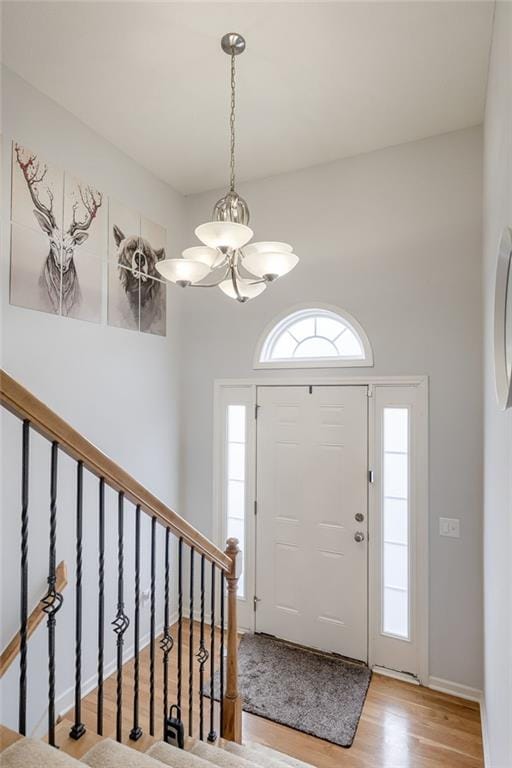 entryway featuring an inviting chandelier, a wealth of natural light, and light hardwood / wood-style floors