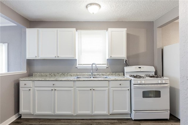 kitchen featuring gas range gas stove, dark hardwood / wood-style flooring, white cabinetry, and sink