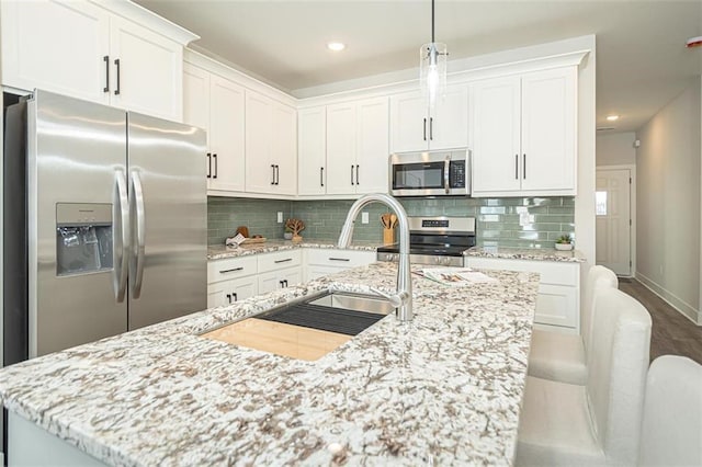 kitchen featuring white cabinetry, stainless steel appliances, and an island with sink