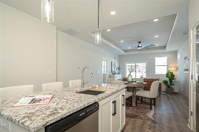 kitchen featuring stainless steel dishwasher, pendant lighting, sink, white cabinetry, and a tray ceiling