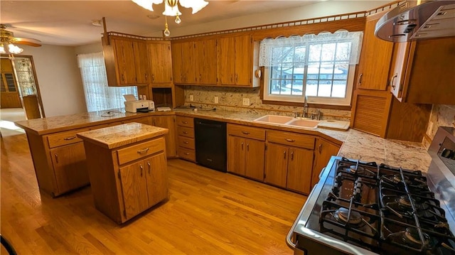 kitchen with stainless steel range with gas stovetop, sink, black dishwasher, a kitchen island, and light hardwood / wood-style floors