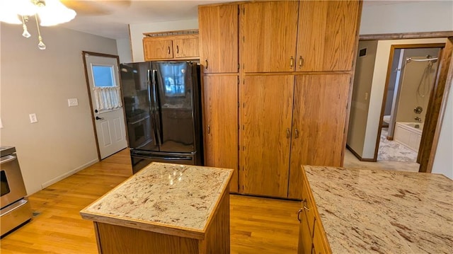 kitchen featuring black refrigerator, stainless steel stove, a center island, and light hardwood / wood-style flooring