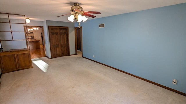 empty room with ceiling fan and light carpet