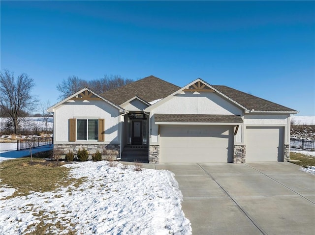 view of front of property featuring stucco siding, an attached garage, fence, stone siding, and driveway