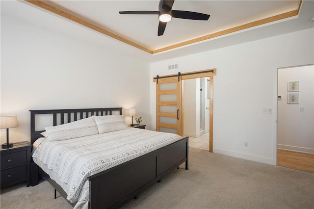 carpeted bedroom featuring a raised ceiling, ceiling fan, and a barn door