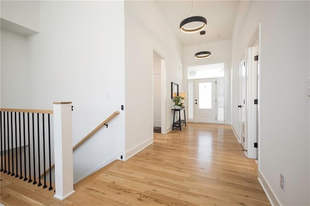 hallway with light wood finished floors, an upstairs landing, and baseboards