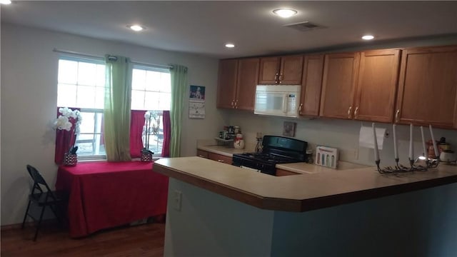 kitchen with kitchen peninsula, black gas range oven, and dark hardwood / wood-style floors