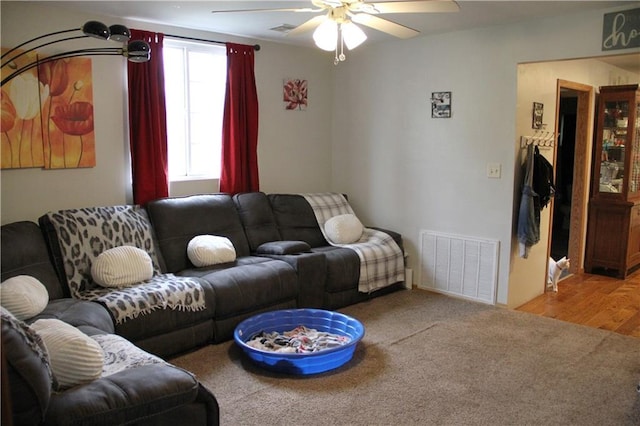 living area with a ceiling fan, visible vents, and carpet