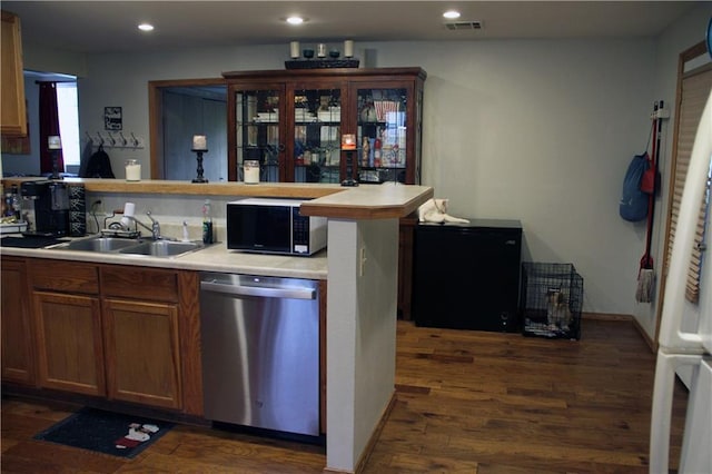 kitchen with a sink, light countertops, stainless steel dishwasher, and dark wood finished floors