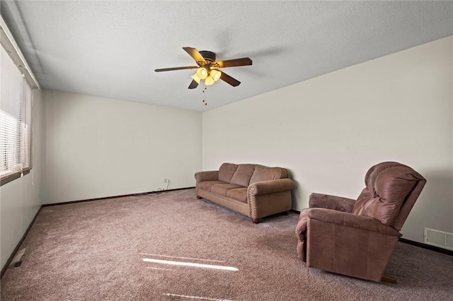 living area with a textured ceiling, carpet, visible vents, and a ceiling fan