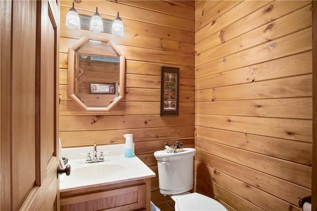 bathroom featuring wooden walls, vanity, and toilet