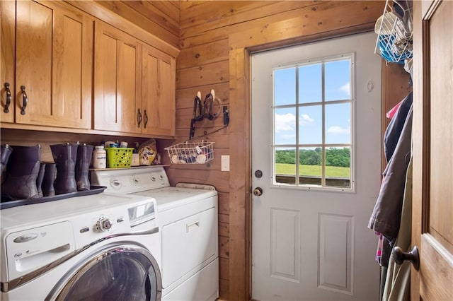 laundry room with cabinets, washer and clothes dryer, and wood walls