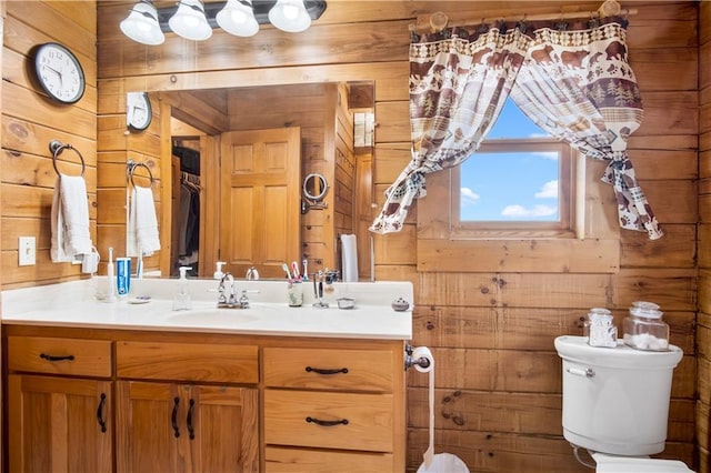 bathroom with toilet, vanity, and wooden walls