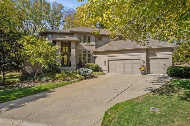 prairie-style home with an attached garage, driveway, and stucco siding