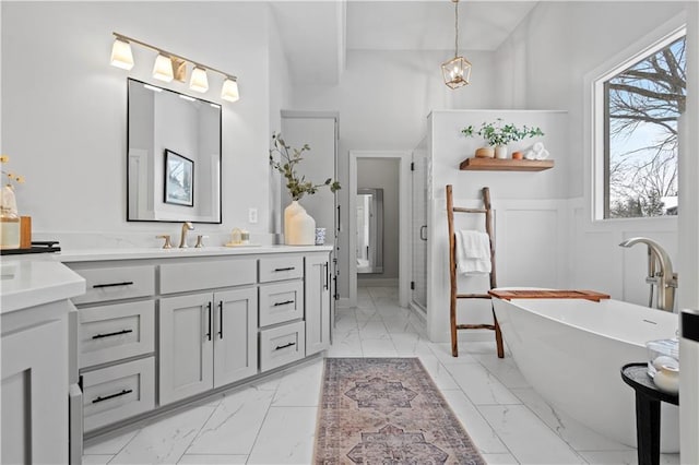 full bath with marble finish floor, a freestanding tub, a stall shower, and wainscoting