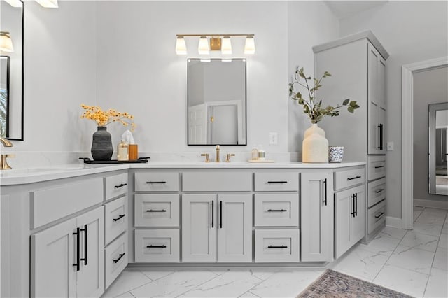 bathroom with marble finish floor, vanity, and baseboards