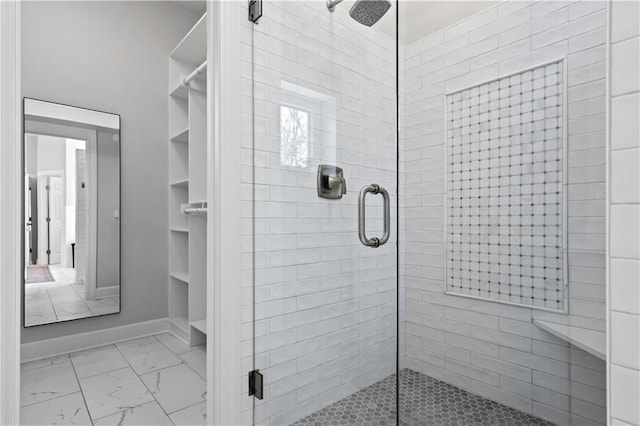 bathroom with marble finish floor, a shower stall, and baseboards