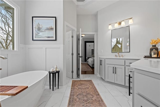 bathroom with a decorative wall, a wainscoted wall, vanity, marble finish floor, and a soaking tub