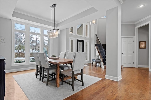 dining area with a chandelier, a tray ceiling, crown molding, and stairs