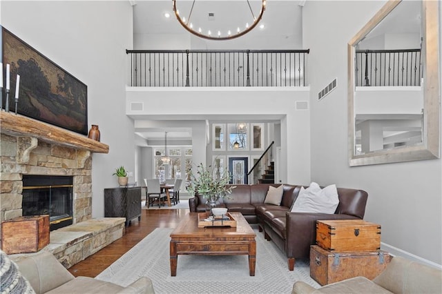 living room featuring a chandelier, visible vents, a fireplace, and wood finished floors