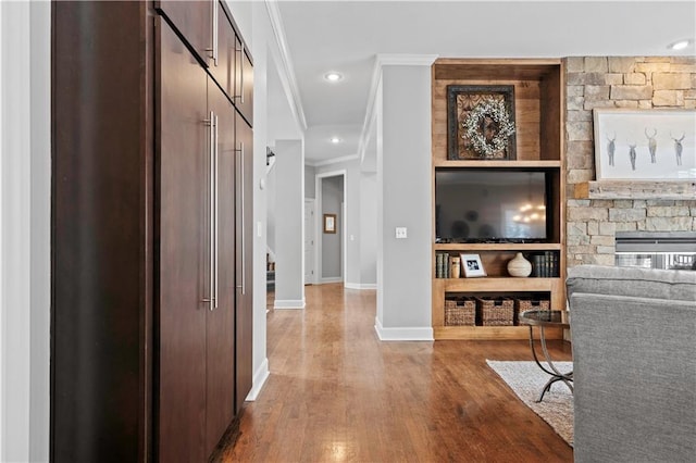 hallway featuring baseboards, ornamental molding, wood finished floors, stairs, and recessed lighting