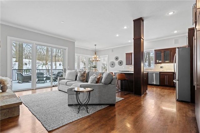 living room featuring dark wood-style floors, crown molding, recessed lighting, and an inviting chandelier