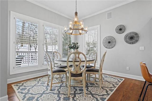 dining room with crown molding, visible vents, wood finished floors, a chandelier, and baseboards