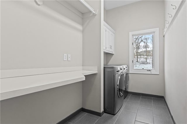 laundry room featuring cabinet space, dark tile patterned floors, baseboards, and separate washer and dryer