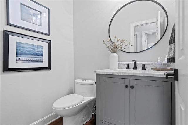 bathroom featuring baseboards, vanity, and toilet